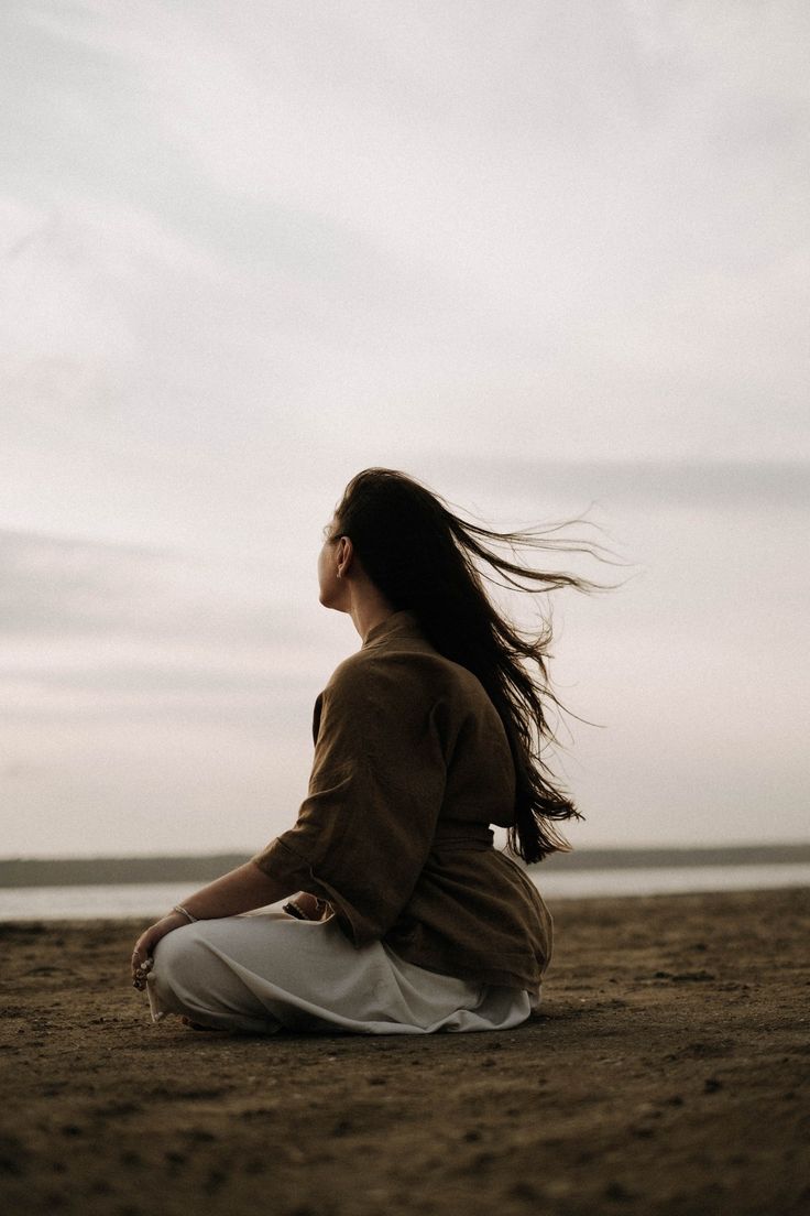 Person sitting peacefully by the ocean at sunset